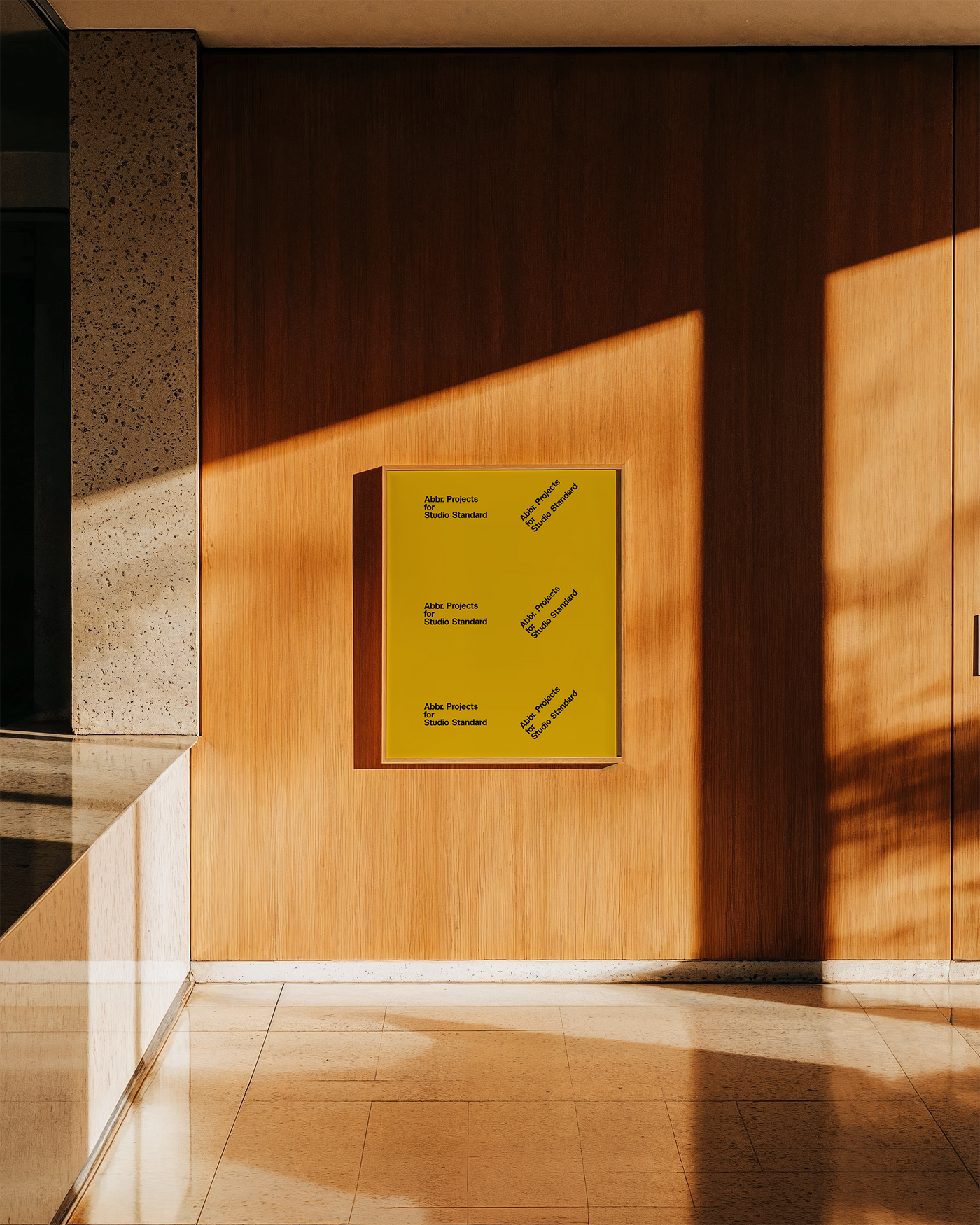 Poster mockup with yellow graphic print displayed on a dark wood-paneled wall with natural light and marble floor