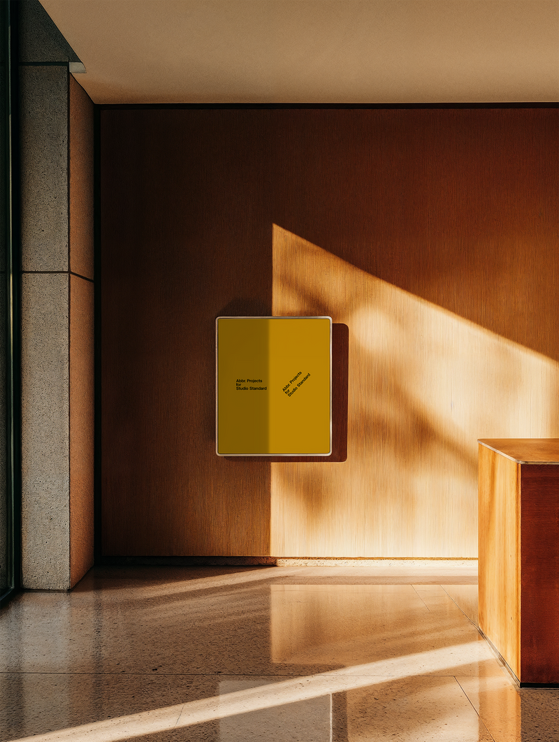 Presentation mockup of a yellow brochure mounted on a warm terracotta wall in a sunlit institutional hallway