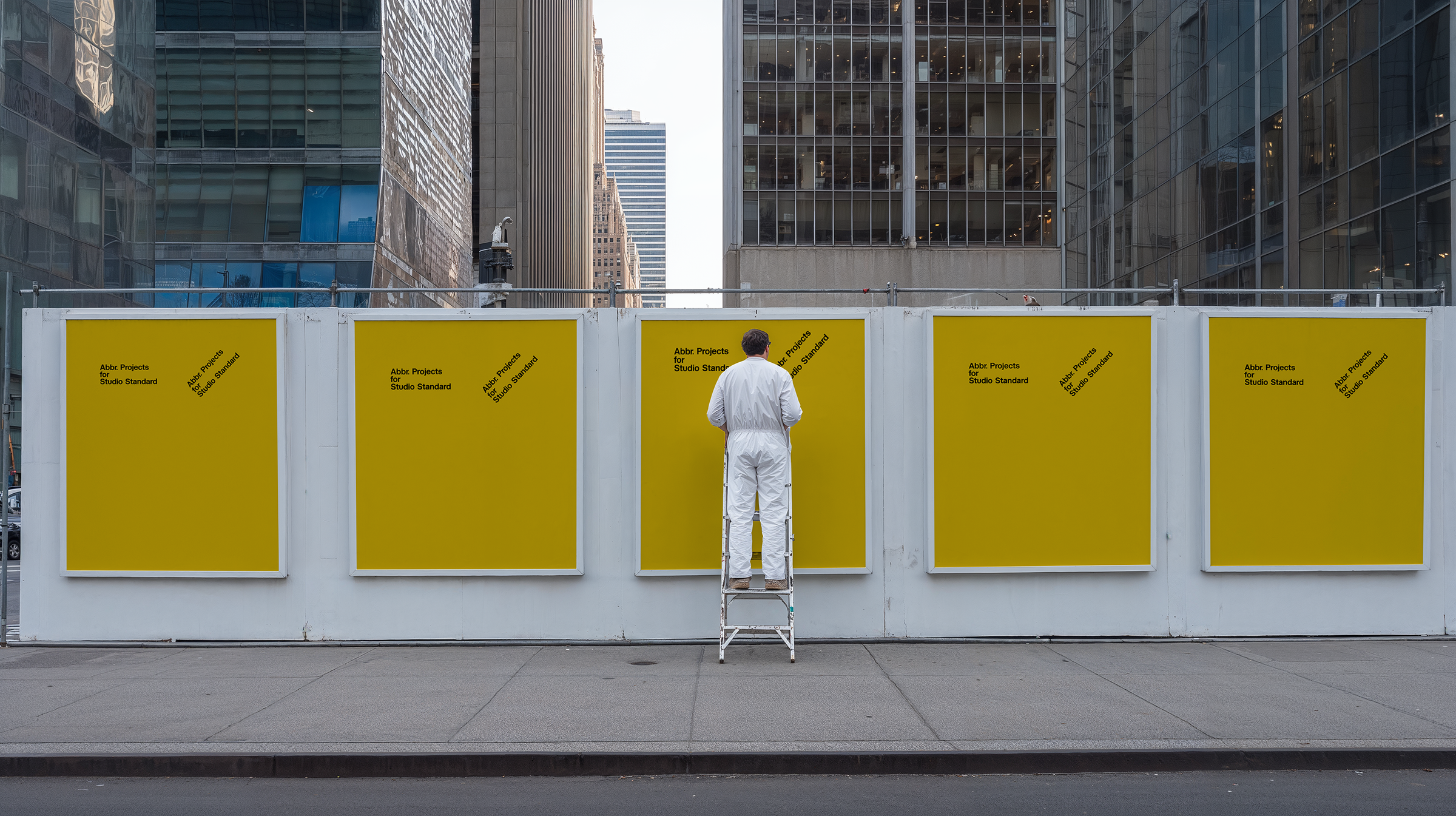 Street hoarding mockup with five yellow posters on a construction barrier, figure in white, city skyline behind