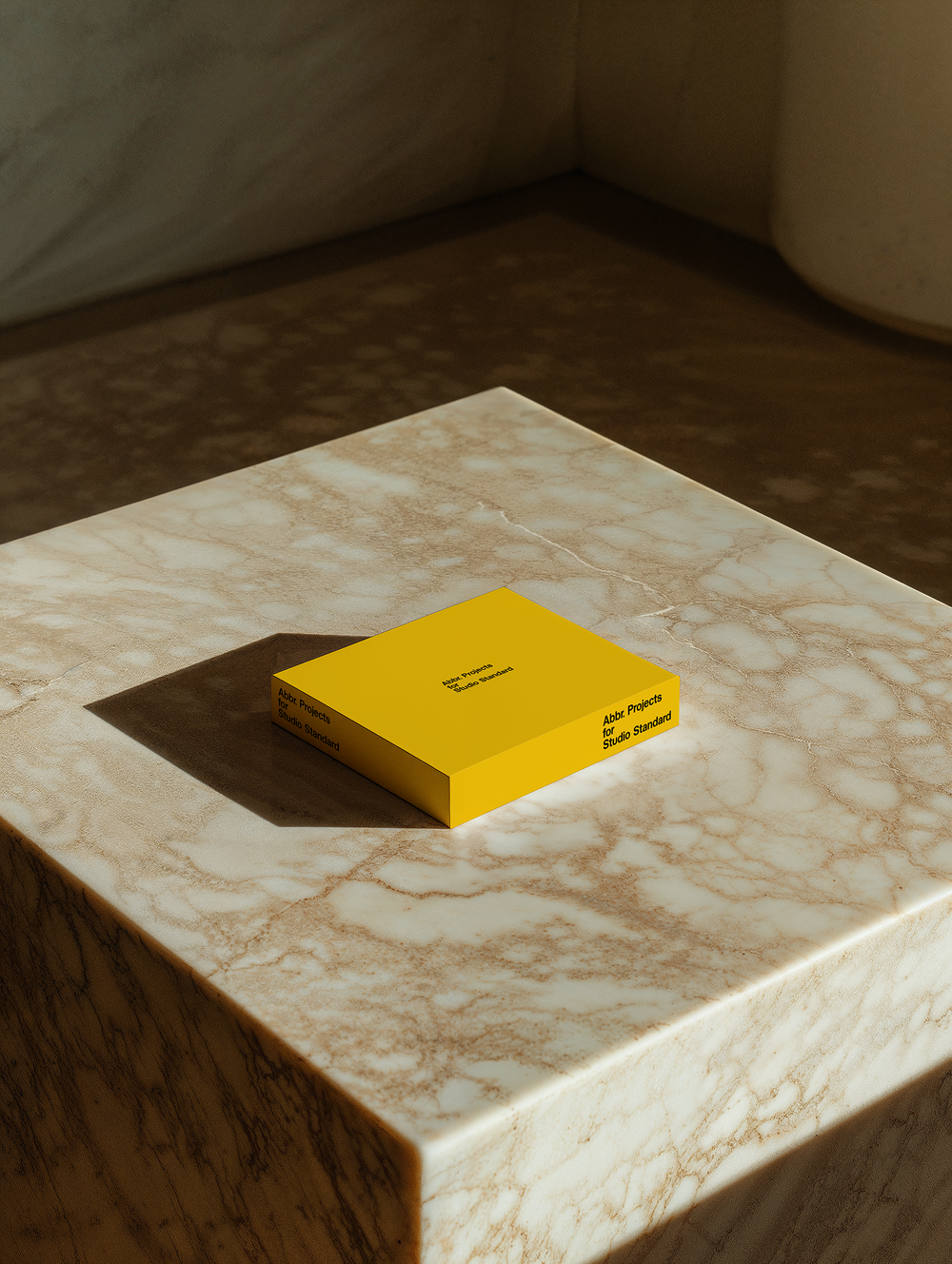 Presentation mockup of a yellow booklet on a marble surface in a warm minimalist interior by Simon Abranowicz