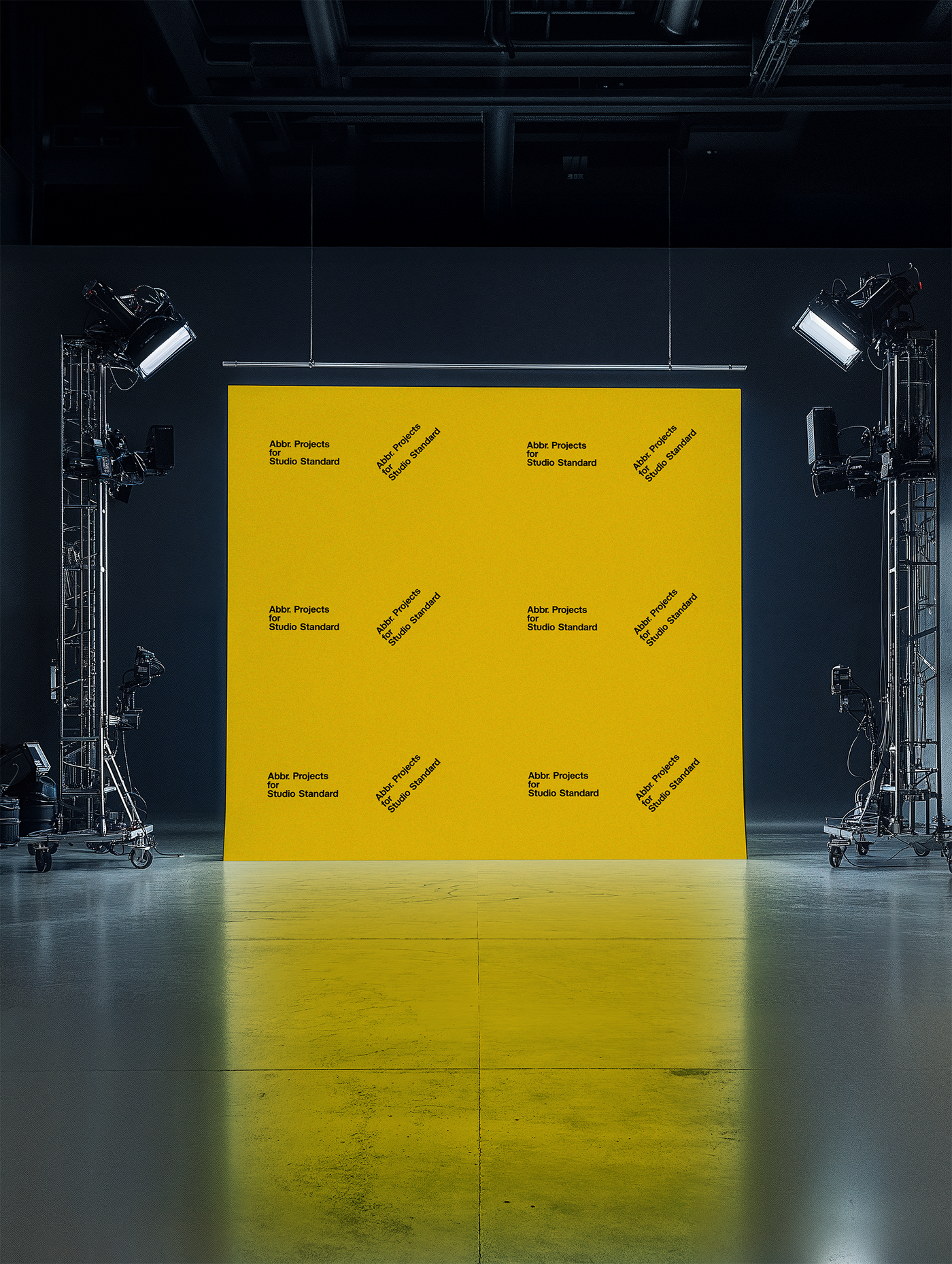 Studio mockup of a yellow step-and-repeat backdrop with professional lighting equipment in a dark photo studio