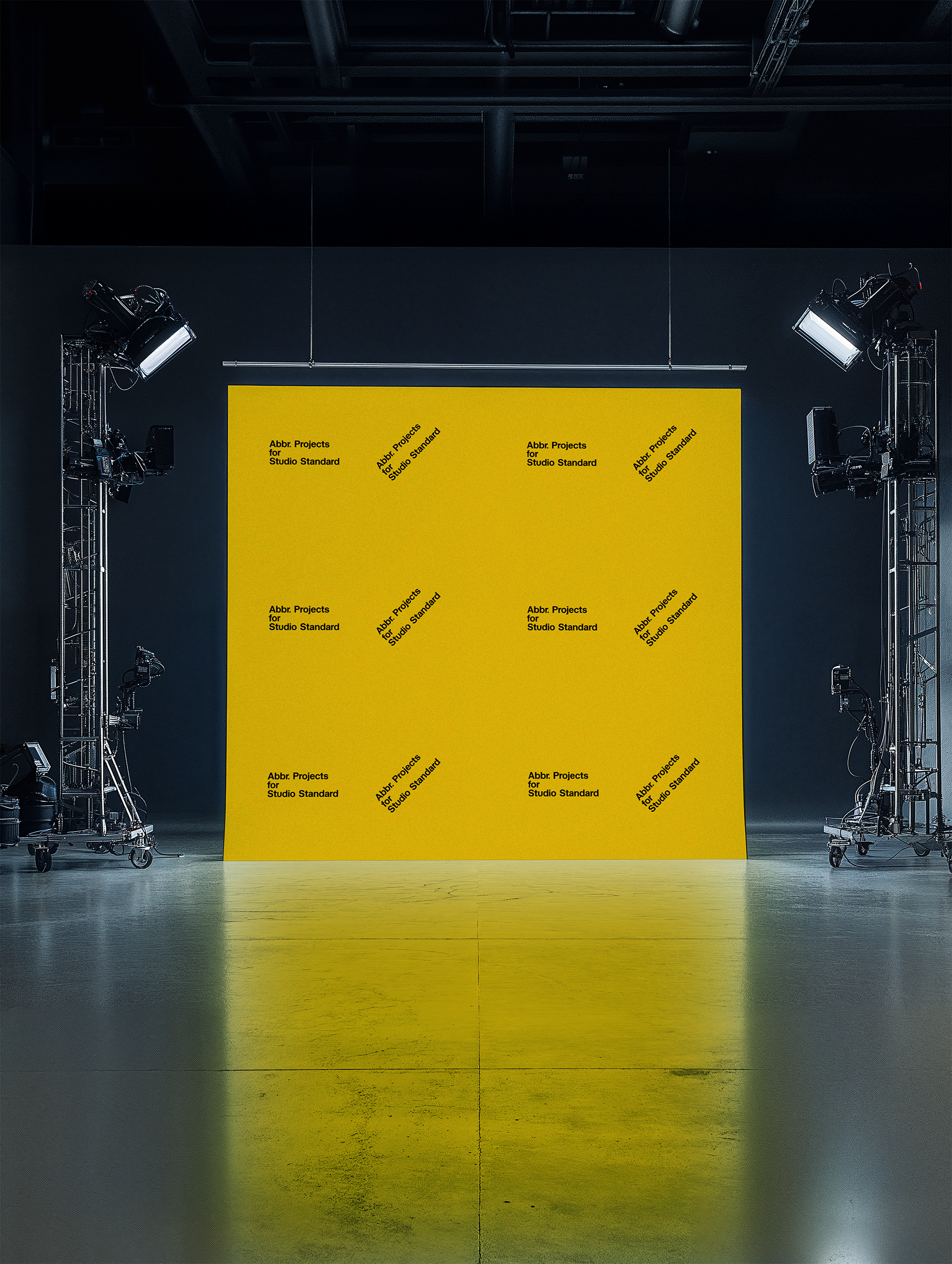 Studio mockup of a yellow step-and-repeat backdrop with professional lighting equipment in a dark photo studio