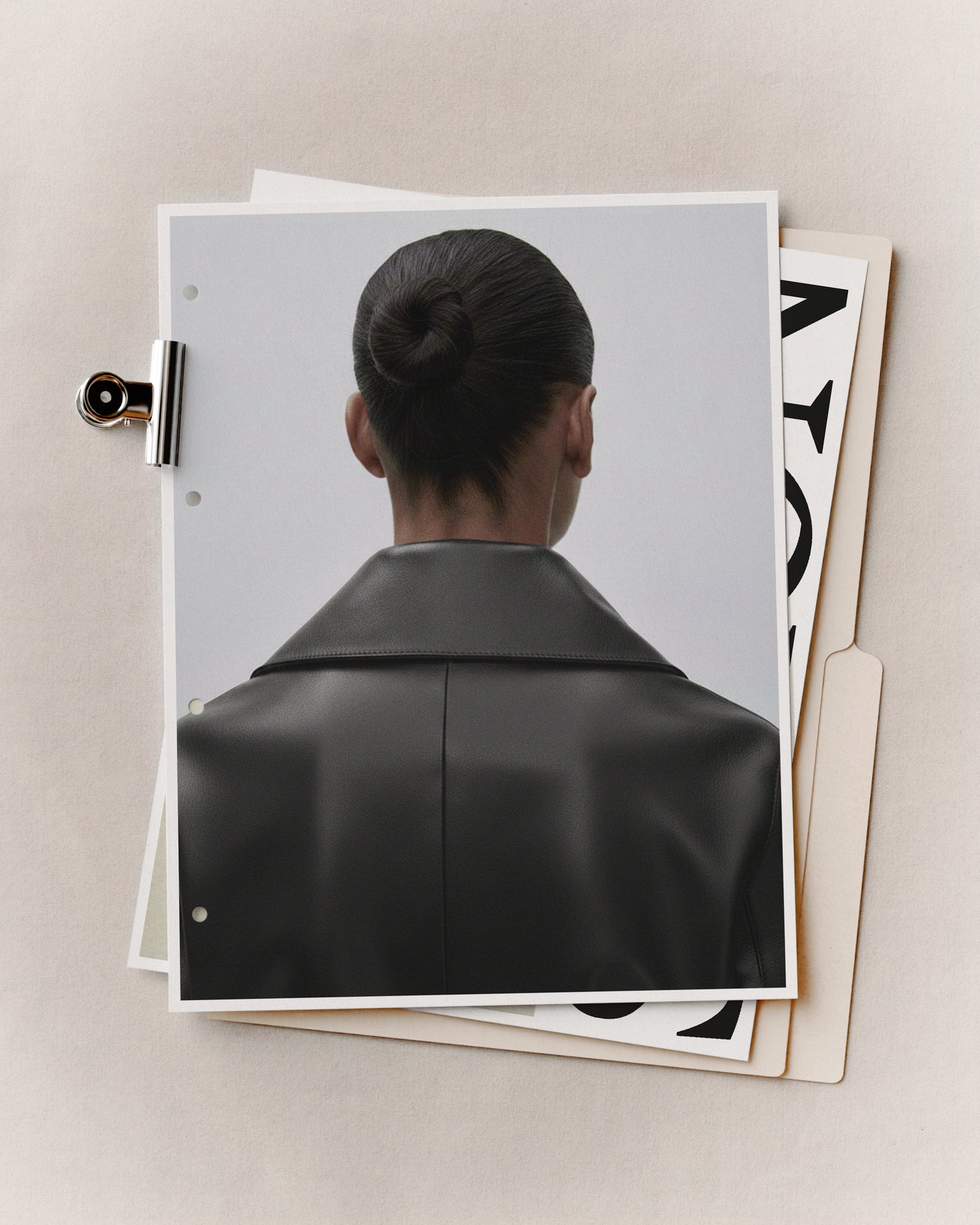Fashion presentation mockup with binder clip holding a punched page over a manila folder and bold typography