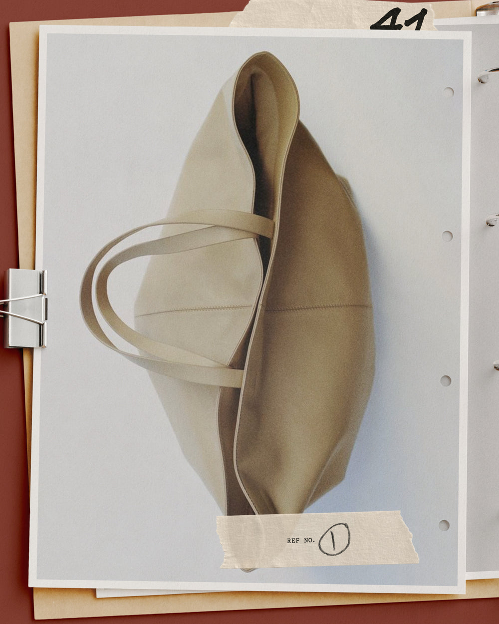 Editorial mockup of a canvas tote on punched binder pages with taped reference label and metal clip