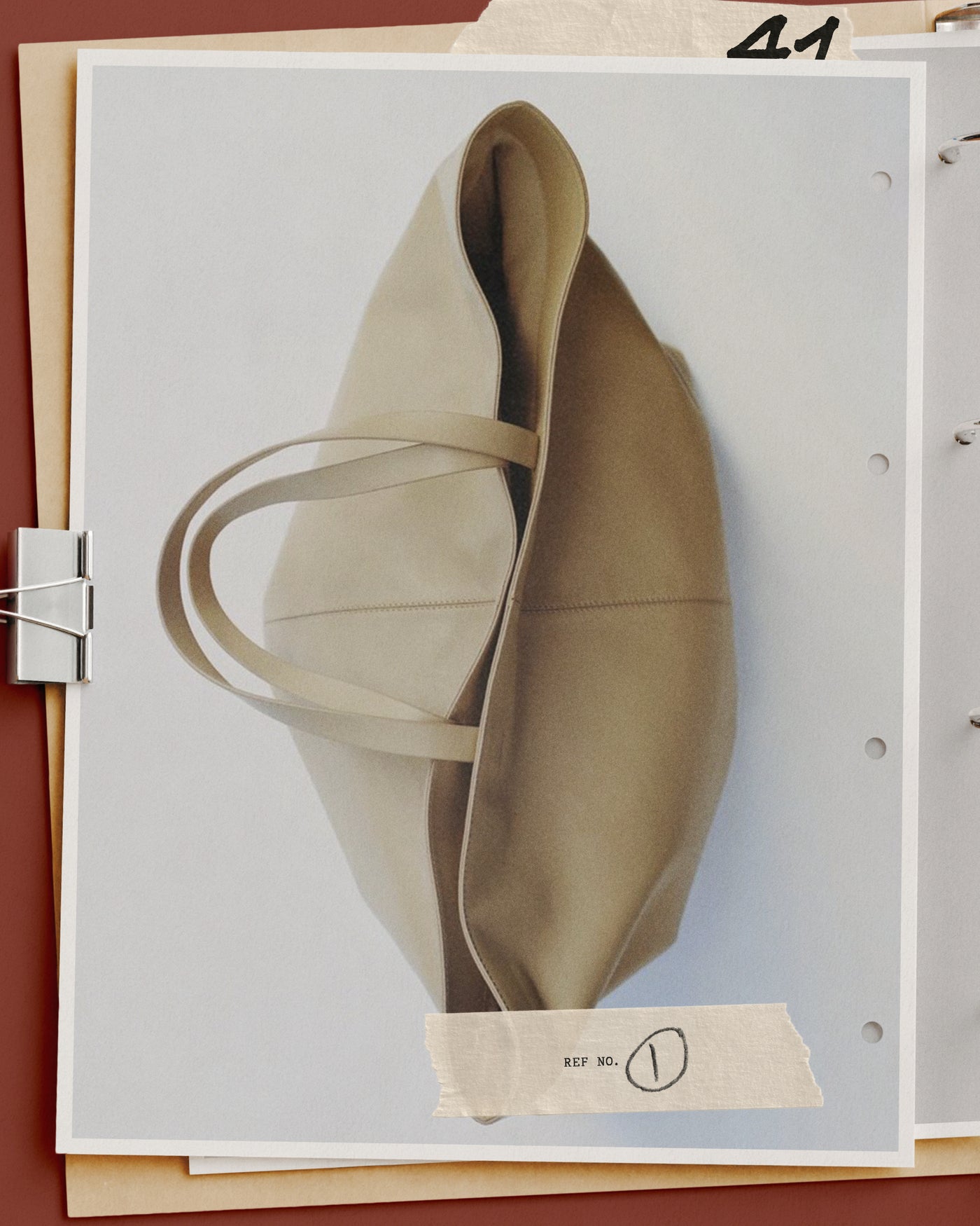 Editorial mockup of a canvas tote on punched binder pages with taped reference label and metal clip