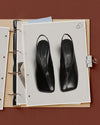 Fashion journal mockup with black slingback heels on punched binder pages held by a silver clip